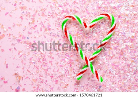 Decoration of Heart made of two lollipops on pink background with glitter. Holiday concept. flat lay