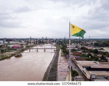 Aerial drone view of Acre river and flag in the amazon. Rio Branco city center buildings, houses, streets, bridges on cloudy day. Brazil. Concept of environment, ecology, climate change and travel. Royalty-Free Stock Photo #1570486675