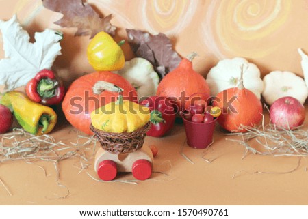 Decorative composition from a toy car, pumpkins, autumn vegetables, fruits, flowers and leaves, the concept of harvesting, natural abundance, Thanksgiving