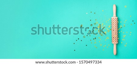 Rolling pin, gold glitter stars on blue background. Top view. Copy space. Christmas baking concept. Holidays composition. Banner for menu, recipe, ingredients.