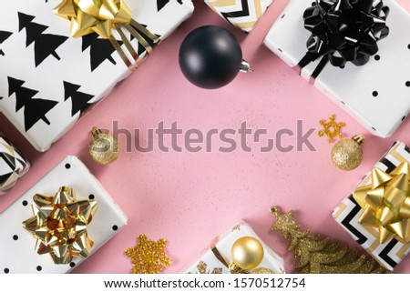 Selection of white, gold and black coloured christmas gift boxes on pink background
