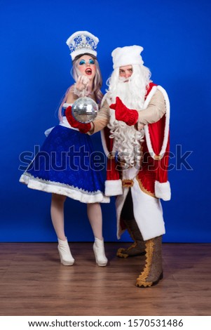 Duet emotional Santa Claus in a red coat and Snow Maiden in a blue suit posing on a blue background