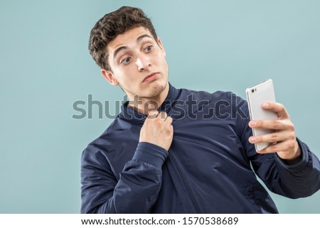 expression and people concept - Young man taking a picture with his cell phone over blue background. Adult over 20 years of age.