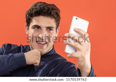 expression and people concept - Young man taking a picture with his cell phone over orange background. Adult over 20 years of age.