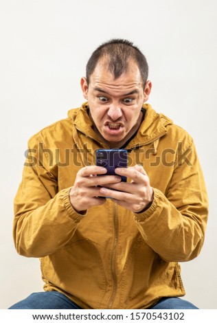 expression and people concept - angry man with cell phone funny face over gray background. Adult over 30 years of age.