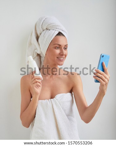 Beauty girl fashion healthy fitness trendsetter blogger posing shows and recommend in hand little plastic bottle with care product to phone video live stream selfie photo camera on white background Royalty-Free Stock Photo #1570553206