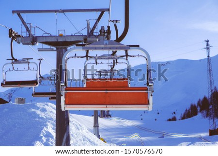 Chairlift or elevated passenger ropeway at ski area. Winter leisure and sports. Mountain snowboard resort. Royalty-Free Stock Photo #1570576570