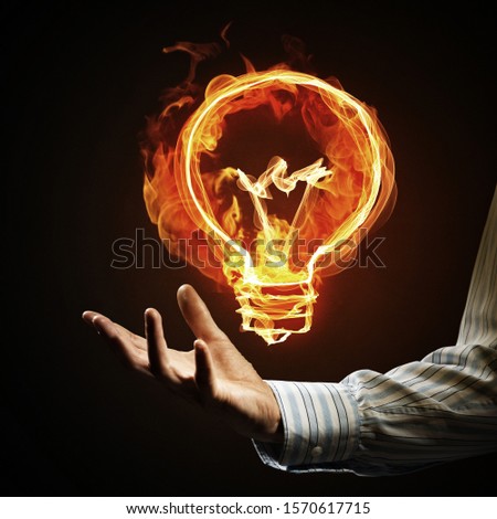 Close of businessman hand holding glowing fire light bulb icon
