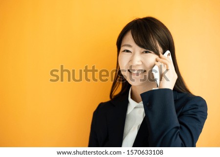 Young business woman talking on smart phone against orange background