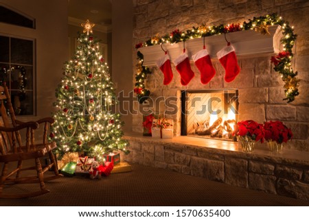 Christmas tree decorated with lights and gifts inside the house with fireplace