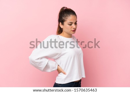 Young brunette girl over isolated pink background suffering from backache for having made an effort