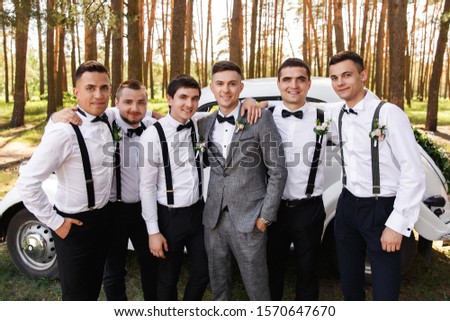 Group wedding photography. Elegant groom in grey suit with groomsmen with black bow ties and suspender at wedding day Royalty-Free Stock Photo #1570647670