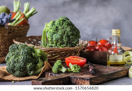 Photo of fresh broccoli around vegetables on cutting board. Raw Picture. Gray background. Image. 