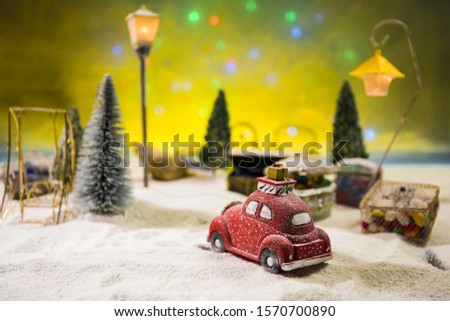 Christmas and New Year holidays concept. Little decorative cute small red car in snow at night. Traditional holiday attributes on snow. Creative artwork decorations. Empty space for your text