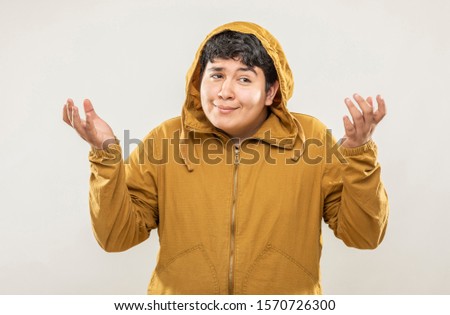 Young fat teenage girl with yellow sweatshirt with innocent face expression on gray background.