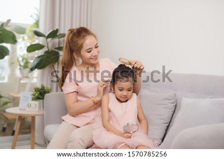 A young mother combing a hair little girl