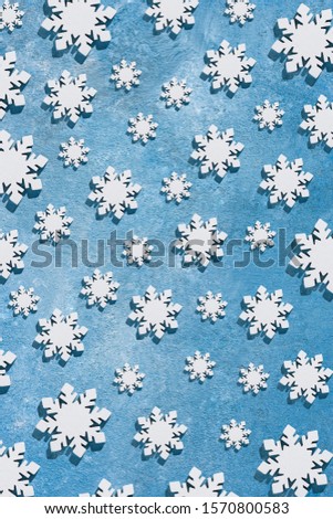 Christmas and New Year pattern made of wooden snowflakes on a blue background. Christmas, winter, new year concept. Flat lay, top view, copy space.