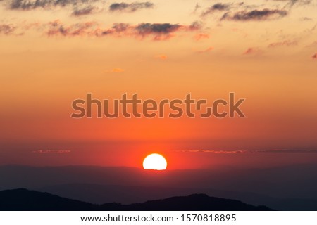Beautiful scenic sunset view above the mountains with cloud moving.Colorful orange sky with sundown in high peak of heaven hill.Nature background concept.