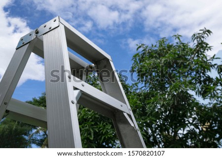Rusty Metallic Ladder on cloudy blue sky and blur tree background  as symbol for success, banner, header, headline, copy space