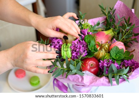 photo from a series of pictures about the process of forming a fruit and flower bouquet. tutorial, do it yourself. photo 35, women's hands correct the details of the bouquet