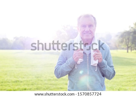 Active senior man standing in park with lens flare
