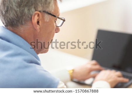 Unrecognizable Elderly Man Using Laptop Looking At Blank Screen Sitting Indoor. Computer Literacy For Senior People