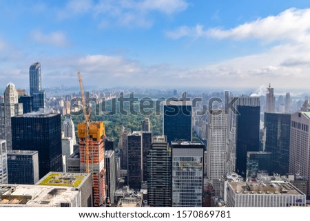 Aerial view of New York with skyscrapers, buildings in construction and central park in the background. Sunny day with some clouds. Concept of travel and construction. NYC, USA.