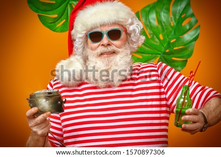 Joyful Santa Claus is relaxing and taking pictures in hot tropical countries. Christmas Holidays, tourist trips to the sea. Bright yellow background. 