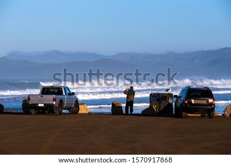Man taking picture of the waves in Pacific Ocean. Sea and mountain view.