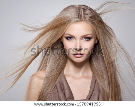 Face of the Beautiful young woman with long straight  hair - posing at studio over gray background Royalty-Free Stock Photo #1570941955