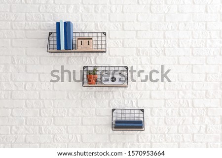 Shelves with decor and books hanging on white brick wall