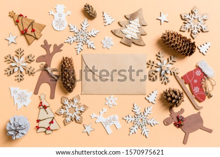 Top view of craft envelope surrounded with New Year toys and decorations on orange background. Christmas time concept