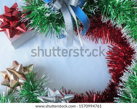 Glossy christmas tinsel decoration and ribbon bows on white background