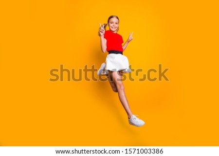 Full length profile photo of pretty funny little lady pretty long tails jumping high showing v-sign symbols wear casual red white dress sneakers isolated yellow color background