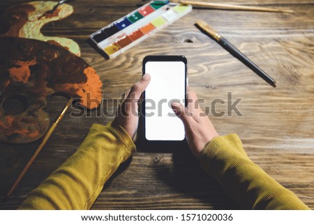 Female artist with mobile phone at table late in evening