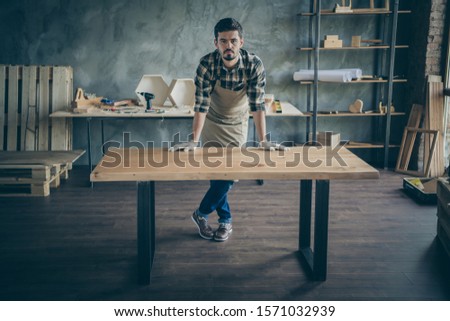 Full body photo of handsome guy master leaning hands on handmade slab table advertising good work selling website own wooden business industry woodwork shop garage indoors