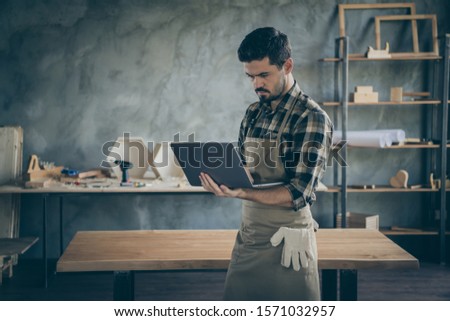 Photo of handsome guy holding notebook website administrator reading new orders checking email box wooden business industry woodwork shop garage indoors