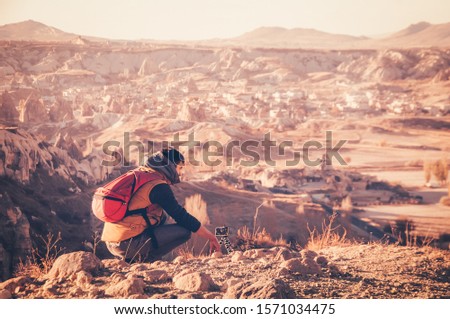 Man traveler taking photos with gorilla pod of beautiful panoramic view in Cappadocia in autumn time