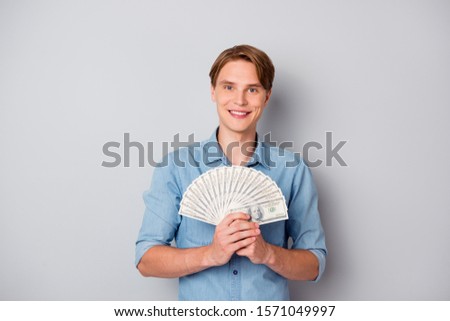 Portrait of positive cheerful guy get milllion dollars in credit bank hold money fan savings wear good looking clothing isolated over grey color background
