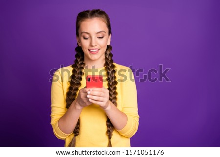 Photo of pretty lady long braids holding telephone hands reading new positive comments wear casual yellow pullover red trousers isolated purple color background