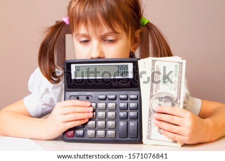 Humorous photo of young serious business girl holding US Dollar bills and calculator
