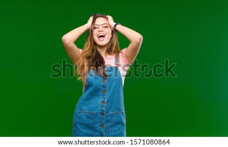 young pretty woman feeling stupefied and scared, fearing something frightening, with hands open up front saying stay away against green background
