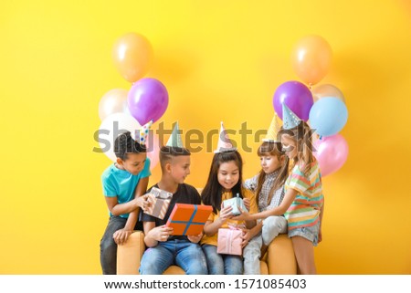 Little children greeting girl with Birthday gifts on color background