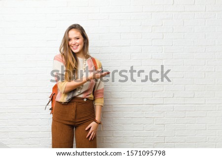 young pretty woman smiling cheerfully, feeling happy and showing a concept in copy space with palm of hand