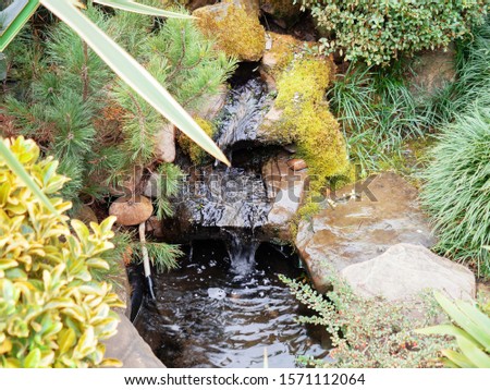 A decorative stream flows over stones in a park