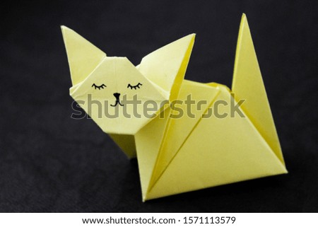 Pretty origami cat on black background