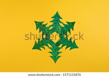 Creative Christmas minimal mockup in trendy yellow with snowflake of six bright green holographic Christmas trees. 