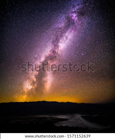 Astrophoto of bright Milky Way taken in Death Valley National Park from Dantes View with Badwater Basin bellow during dark night without the Moon. Photo of the galaxy universe with many stars.