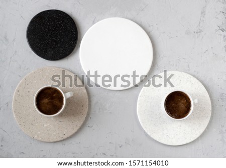 Round coasters made of artificial stone tabletop on a white background. Food stand. Two coffee mugs top view	 Royalty-Free Stock Photo #1571154010