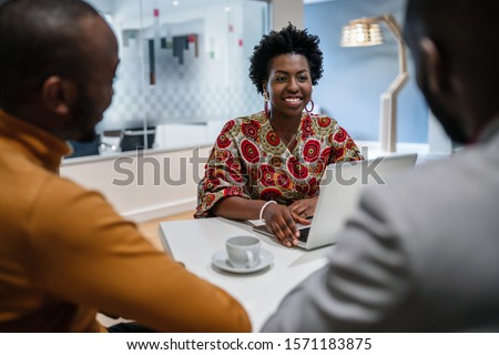 Traditional dressed black African business woman financial bank adviser in meeting with customer. African pattern Royalty-Free Stock Photo #1571183875